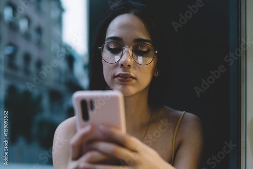 Quadro su tela Young woman chatting via smartphone on street windowsill