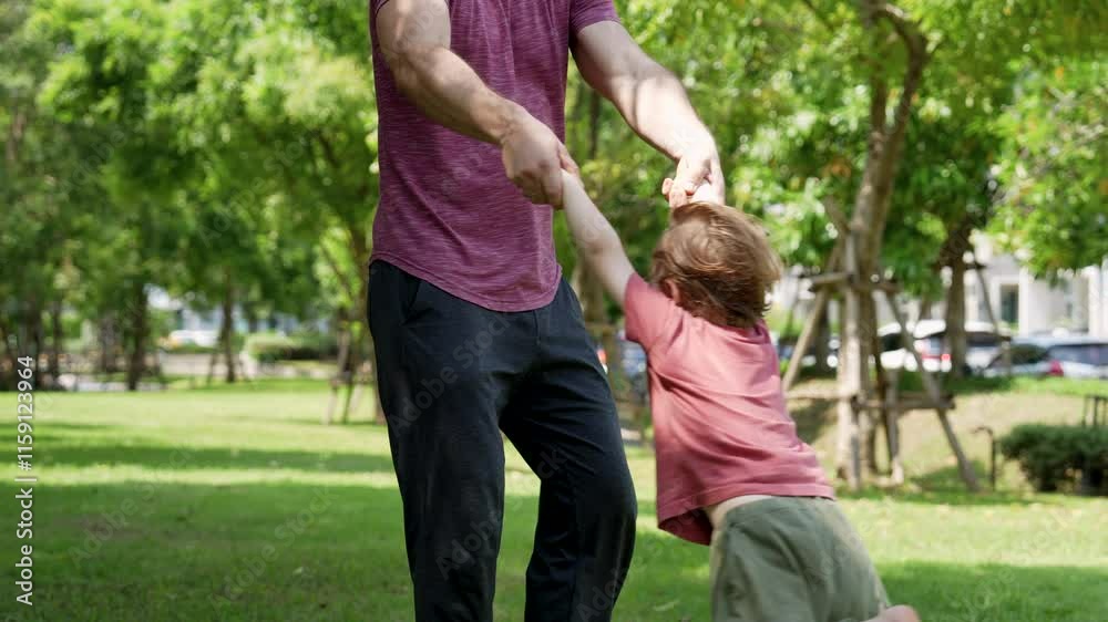 Father and son having a good time together. Dad lifts son hands, swing and turn around. Father and son having a good time together. Dad lifts son hands, swing and turn around.