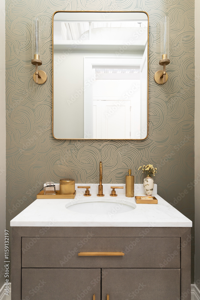 Obraz premium A bathroom sink detail with a gold faucet and decorations, a patterned wallpaper, white marble countertop, and a snake skin cabinet.