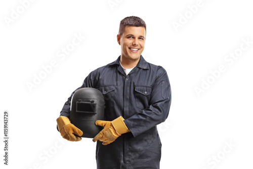 Welder in a uniform holding a protective helmet and smiling at camera