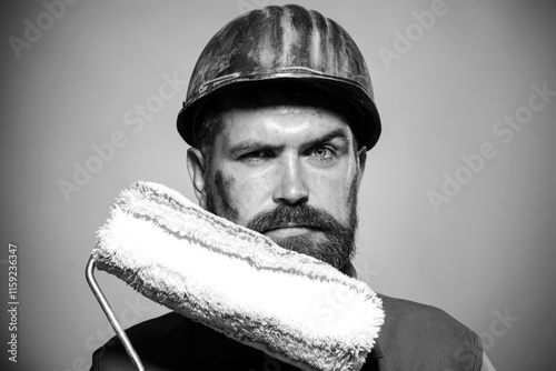 Serious house painter with roller for painting walls. Male painter in hard hat with painting roller. Room painting job. Professional painter in protective helmet with paint roller. Black and white. photo