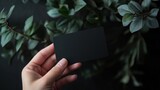 Sleek black gift card held by hand surrounded by lush greenery in an elegant setting for branding and marketing usage. Generative AI