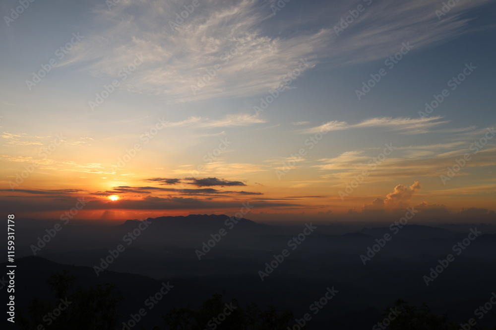 The picture depicts a sunrise on a countryside landscape with foggy mountains and clouds. The picture depicts a sunrise on a countryside landscape with foggy mountains and clouds.