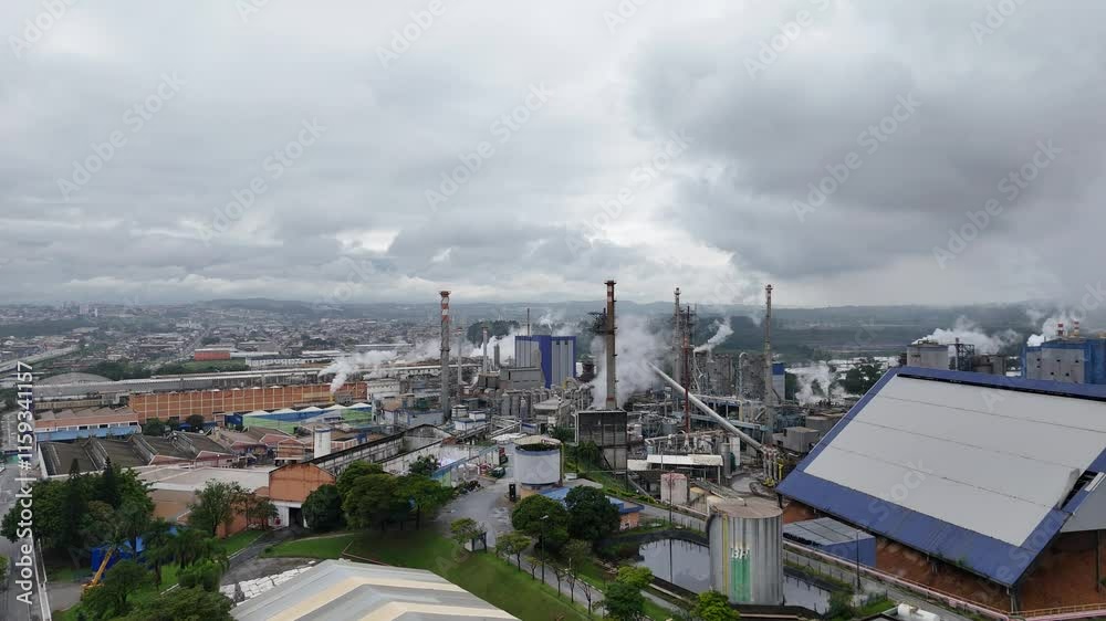 Vídeo de sobrevoo em uma indústria de papel e celulose, mostrando as chaminés e caldeiras em operação, com a produção a todo vapor, capturando o ambiente industrial