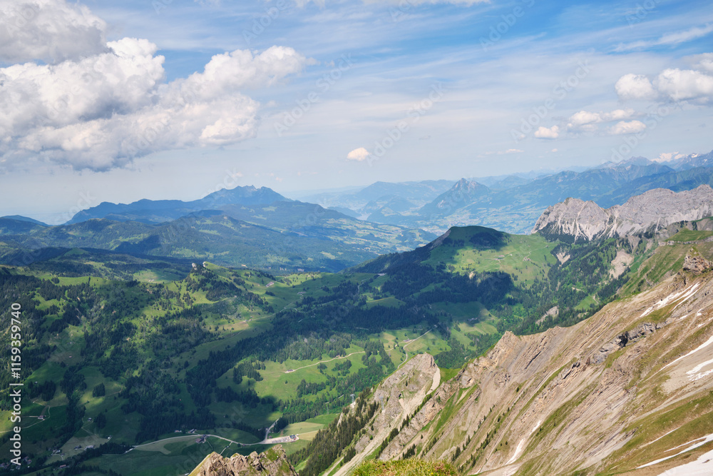 Stunning panoramic view of the Swiss landscape in Brienz, showcasing lush green valleys, rugged mountains, and a clear blue sky with fluffy clouds. Stunning panoramic view of the Swiss landscape in Brienz, showcasing lush green valleys, rugged mountains, and a clear blue sky with fluffy clouds.