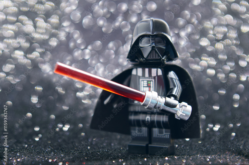 Naklejka premium Lego minifigure of Darth Vader from Star Wars with lightning sword isolated on black. Editorial illustrative image of popular plastic constructor.