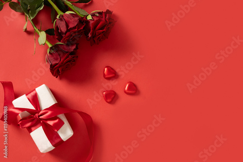 Obraz na płótnie Valentine's day romantic gift, bouquet of red roses and heart shaped chocolate sweets on red background. View from above. Romantic greeting card. Copy space. w salonie