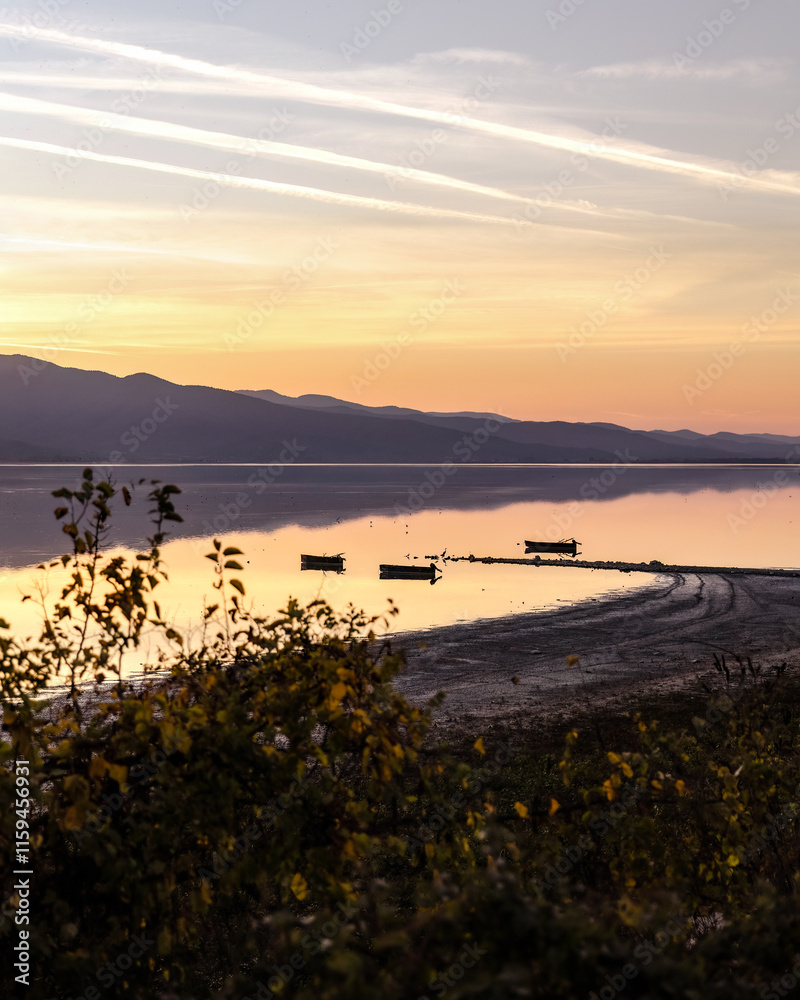 Fototapeta premium Beautiful sunset scenery on Kerkini lake Macedonia Greece, golden hour and sunrise, boats and water reflection, autumn leaves
