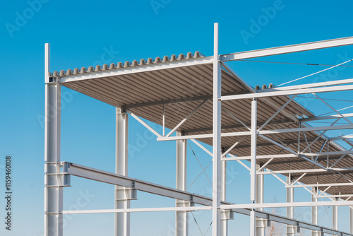 Modern Steel Frame Construction with Corrugated Roof Panels Against Clear Blue Sky photo