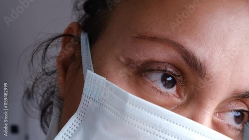 Sick woman in mask looks out the window