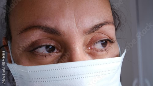 Sick woman in mask looks out the window