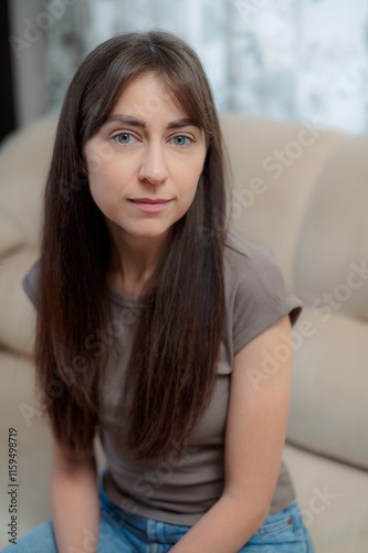 peace woman sitting comfortably on a gray couch at home, smiling and relaxing in soft natural light during the afternoon Free Download peace woman sitting comfortably on a gray couch at home, smiling and relaxing in soft natural light during the afternoon - GFXLoad