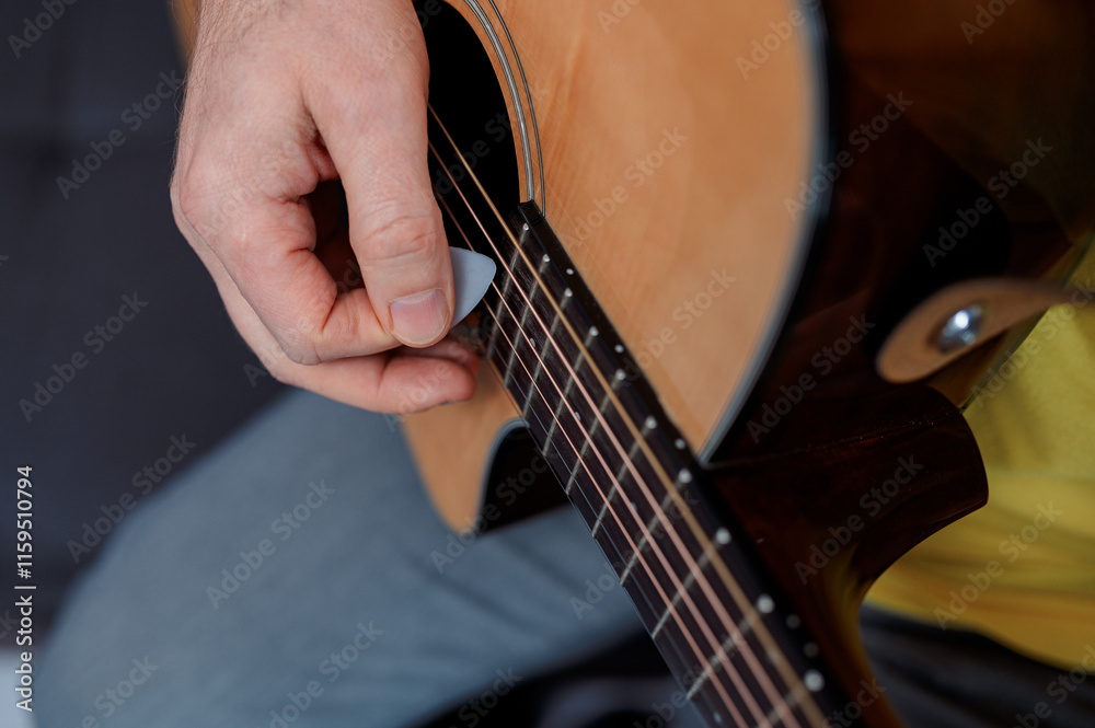 Fototapeta premium Guitarist on acoustic guitar playing melody. Close up musician instrument with pick in hand