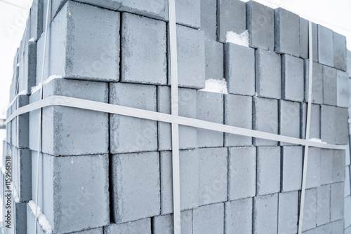 A wellarranged stack of sturdy concrete blocks that are securely tied together with a durable white strap for added stability and ease of transport, showcasing a reliable building material photo