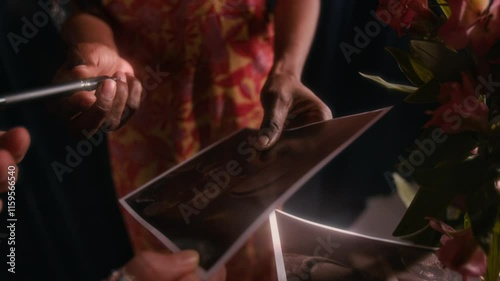 Close-up shot of hand of anonymous female celebrity signing autographs for her fans on photographs after successful concert, one fan holding pink flowers