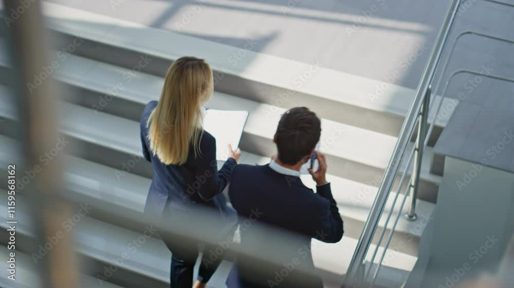 Business partners discussing documents walking up stairs modern office building