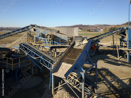 Elements of equipment for the extraction and sorting of rubble. Production of construction materials. Metal construction for working with stone and rocks. Slag of gravel under the conveyor belt photo