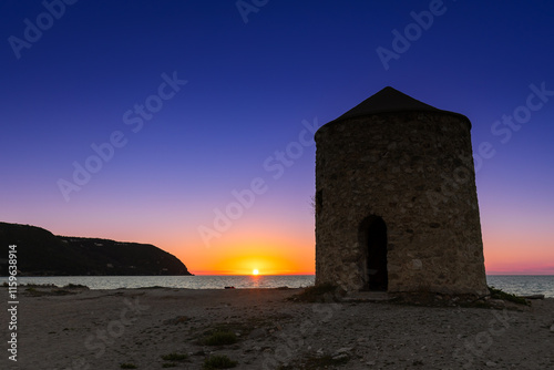 Kolorowy zachód słońca  z widokiem na stary wiatrak nad morzem na piaszczystej plaży, grecka wyspa Lefkada, krajobraz photo