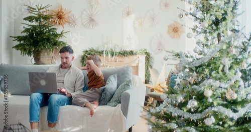 Little Boy and Dad Sitting on Couch Doing Online Christmas Shopping photo