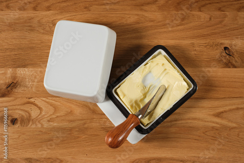 A butter dish lying on a wooden table, together with a grease knife photo