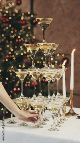 A pyramid of glasses with champagne falls. A woman's hand takes the bottom glass of sparkling wine.