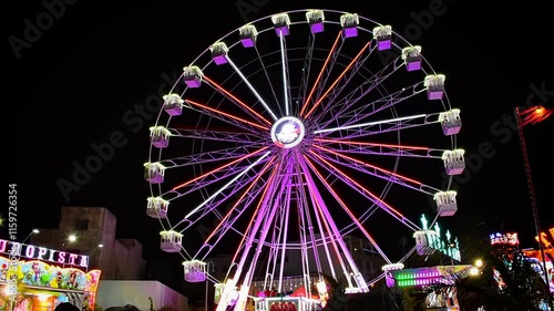 Ferris wheel turns in dark night at Christmas carnival. Fun holidays at Arrecife, Lanzarote, Canary Islands, Spain.