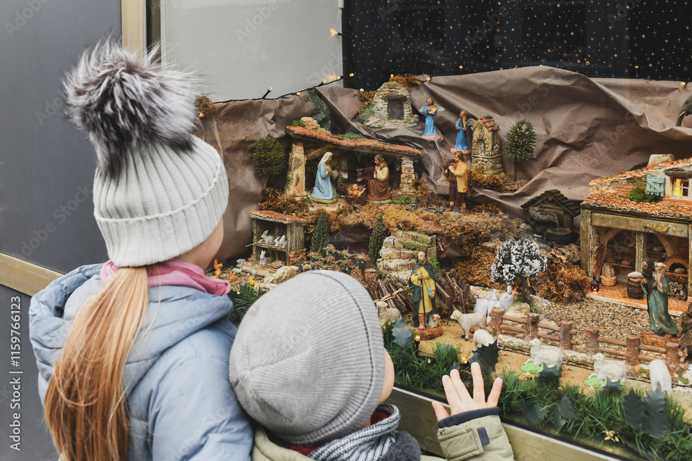 Obraz premium The kids looking at a Christmas nativity scene with baby Jesus Creche Figurines in a shop window