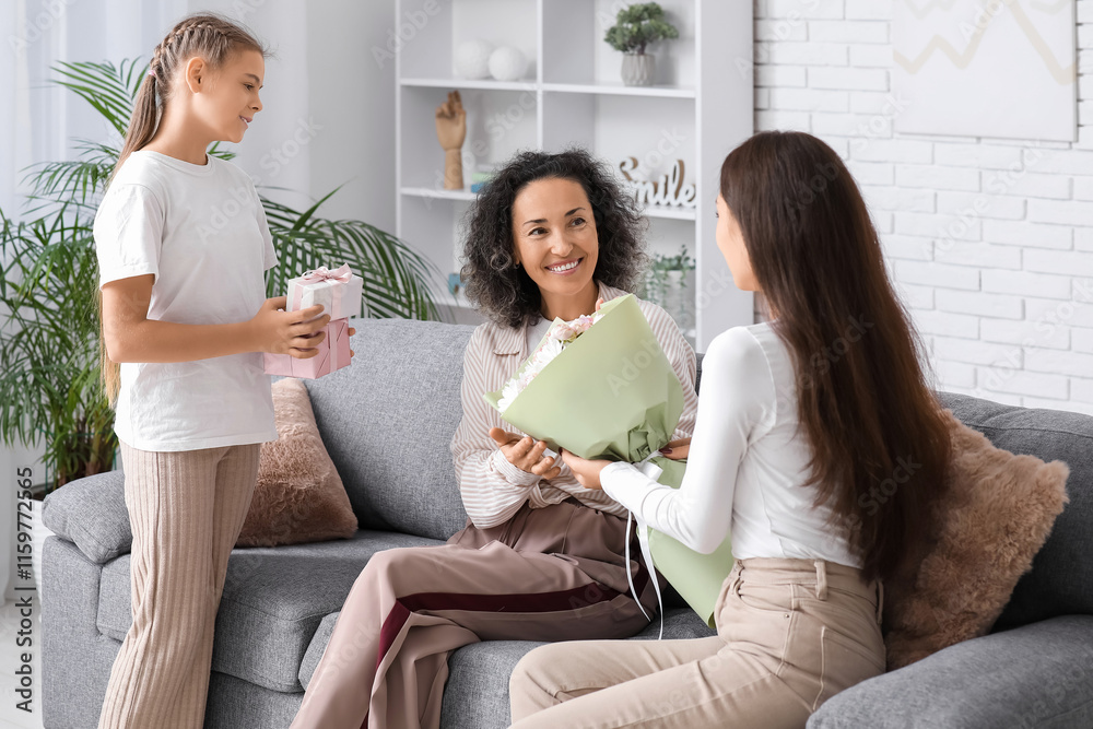 Mature woman receiving gifts from her daughters at home Mature woman receiving gifts from her daughters at home