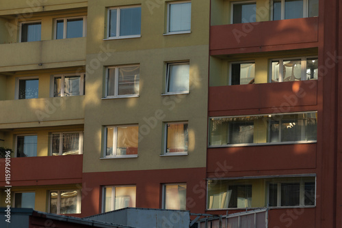 An exterior view showcasing a vibrant and colorful residential building featuring numerous windows and balconies. Light and shadows