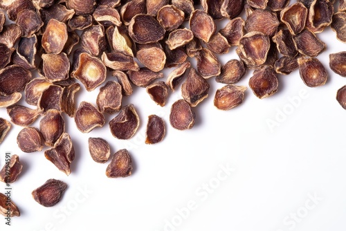 Brown dried jujube seeds sit on a white backdrop They are used in desserts soups and beverages Close up photo