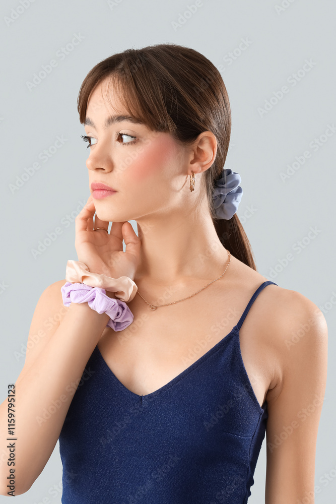 Young woman with ponytail and scrunchies on light background Young woman with ponytail and scrunchies on light background
