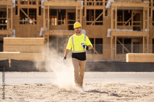 Construction worker having coffee break on construction site. A man builder in a helmet and goggles drinks a hot drink. Mature construction worker taking a break on site and drinking a coffee beverage