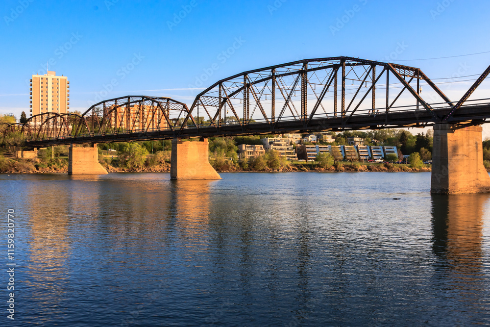 Fototapeta premium A bridge spans a river with a city in the background