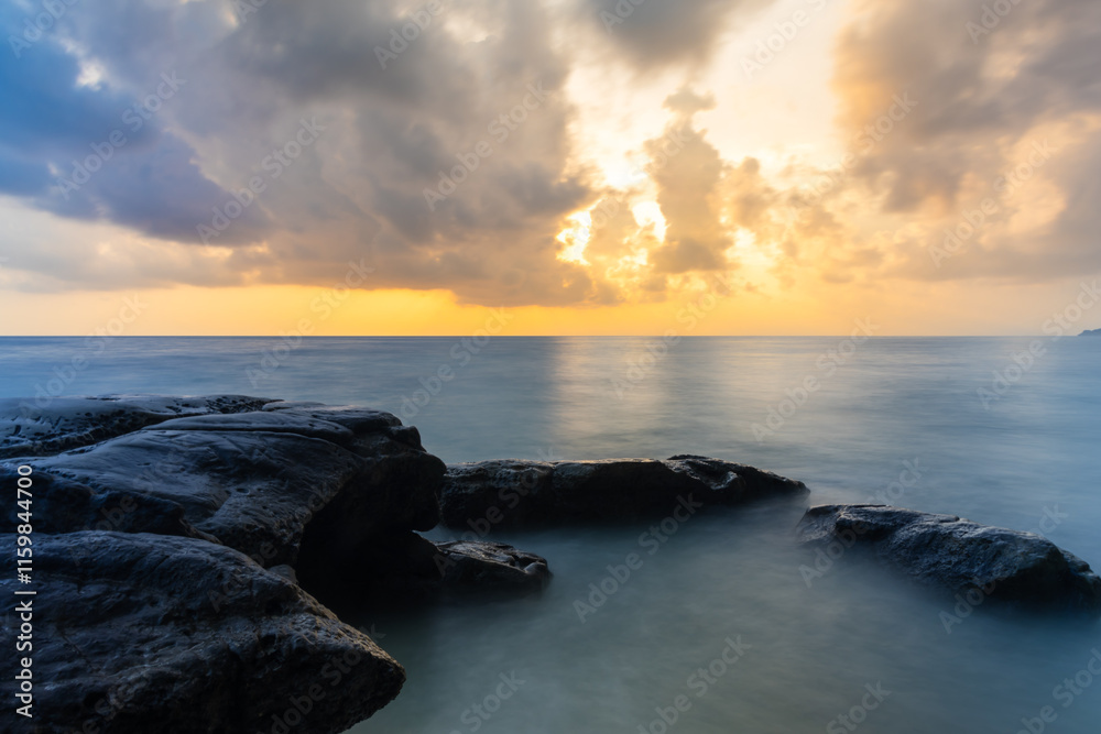Obraz premium sunrise dramatic sky over sea horizon from rocky shore at dawn long exposure shot