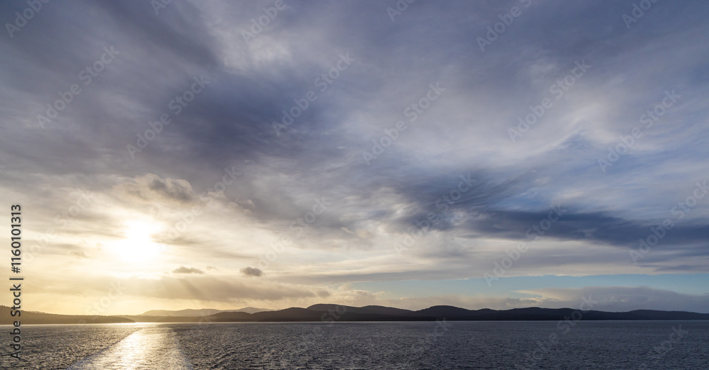 Fototapeta premium Sunset Over Coastal Waters and Distant Mountain Range