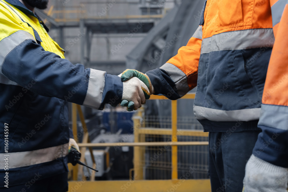 Industry workers shaking hands on background workplace concentrating plant of copper and gold. Concept of interaction between metallurgical engineer and management Industry workers shaking hands on background workplace concentrating plant of copper and gold. Concept of interaction between metallurgical engineer and management