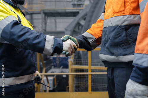 Industry workers shaking hands on background workplace concentrating plant of copper and gold. Concept of interaction between metallurgical engineer and management photo