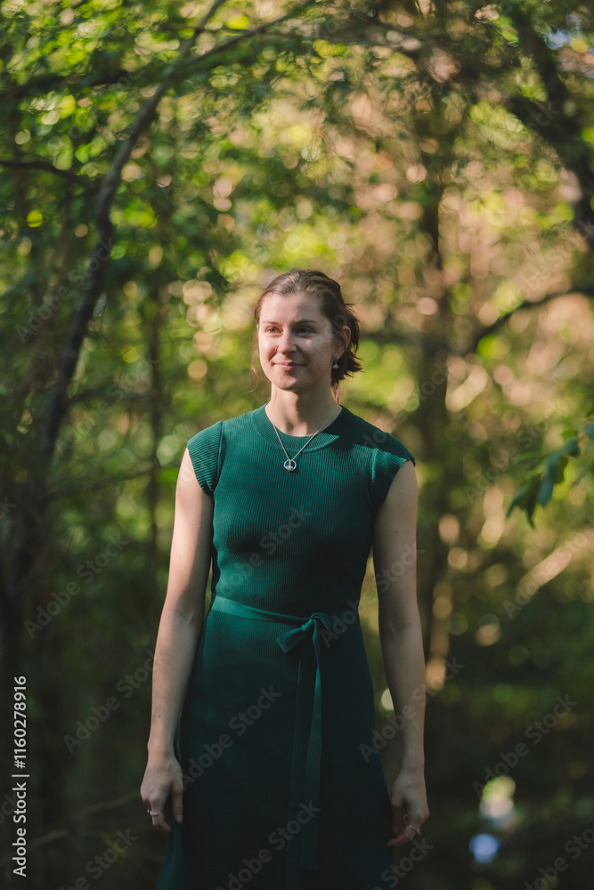 A young woman stands gracefully in a forest clearing, wearing a green dress and black boots. Sunlight filters through the dense trees, creating a serene, natural atmosphere of dappled light and shadow A young woman stands gracefully in a forest clearing, wearing a green dress and black boots. Sunlight filters through the dense trees, creating a serene, natural atmosphere of dappled light and shadow