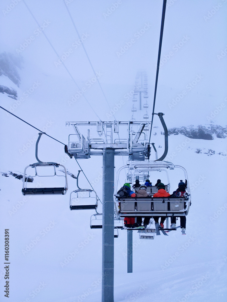 Chairlift carrying skiers into the clouds on a snowy day in Val Thorens. Chairlift carrying skiers into the clouds on a snowy day in Val Thorens.