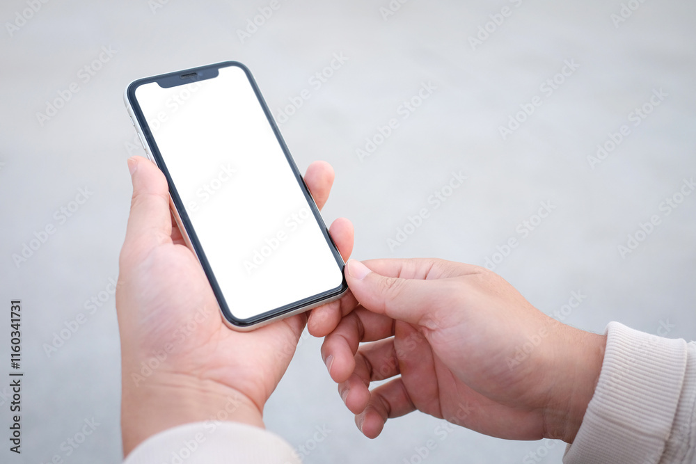 Young man holding a smartphone with a blank white screen outside Young man holding a smartphone with a blank white screen outside