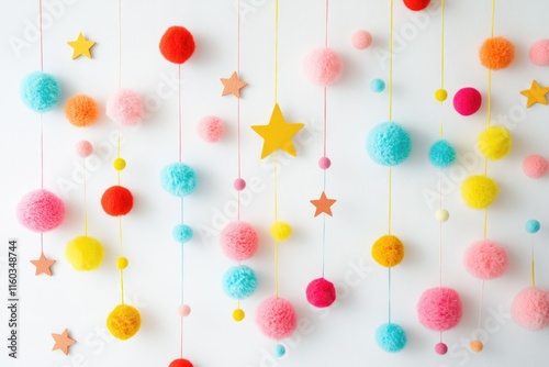 Colorful pom-poms and stars hang from strings against a white wall, creating a cheerful and playful decoration.