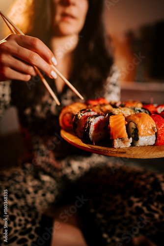 Woman in pajamas savoring fresh sushi while relaxing in bed during a cozy evening