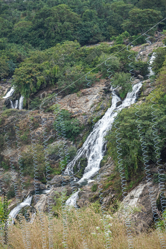 India, Karnataka, Barachukki Waterfallss, a close up of a hillside next to a rock wall with Devon Falls in the background photo