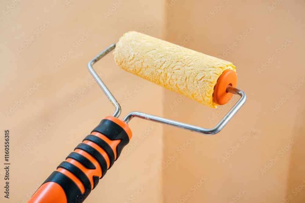 Fototapeta premium A paint roller with orange handle and yellow paint roller head, ready for painting.