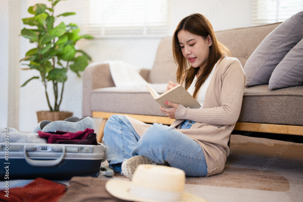 Asian woman planning her travel at home, ticking off a detailed packing list as she packs travel essentials into her suitcase.woman organizing everything she needs for a successful trip. Asian woman planning her travel at home, ticking off a detailed packing list as she packs travel essentials into her suitcase.woman organizing everything she needs for a successful trip.