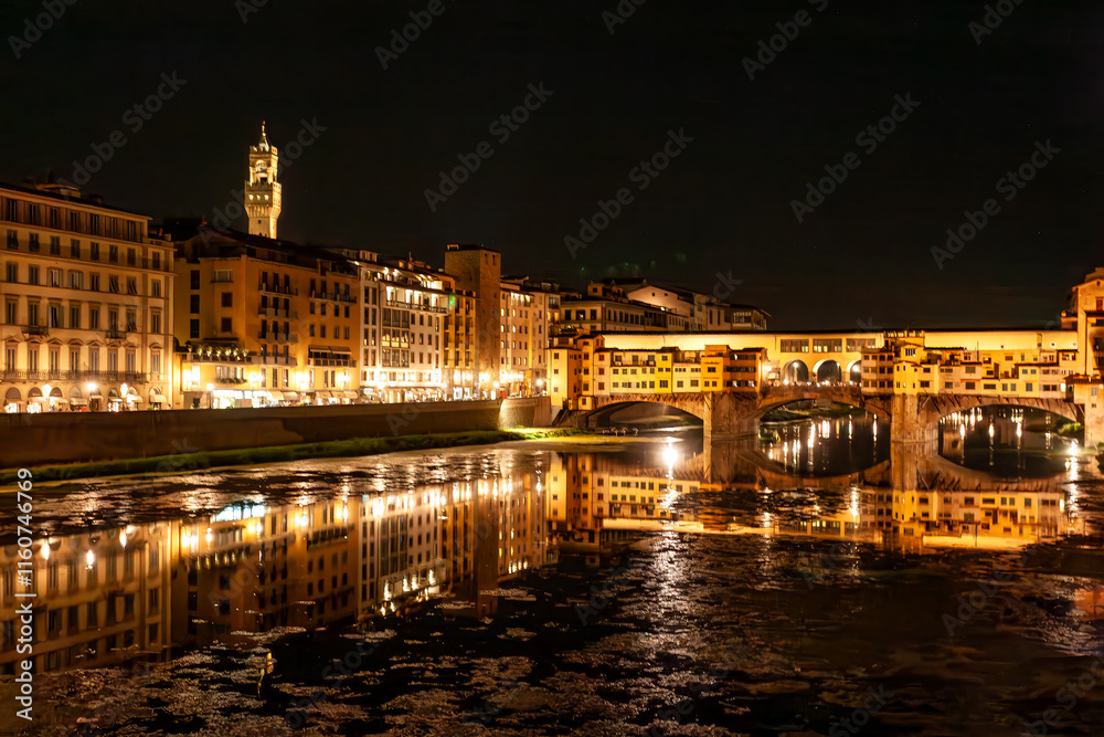 Fototapeta premium Night falls over Florence, illuminating the Ponte Vecchio and surrounding buildings. The tranquil Arno River reflects the vibrant lights, creating a magical atmosphere in Tuscany.
