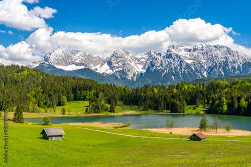 Fototapeta Naklejka Na Ścianę i Meble -  Geroldsee lake surrounded by wooden huts and the snow-covered Karwendel mountains under a clear blue summer sky in Bavaria, Germany