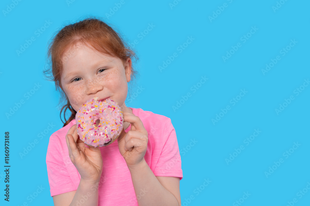Girl enjoying a colorful donut in a bright blue setting with a joyful expression Girl enjoying a colorful donut in a bright blue setting with a joyful expression