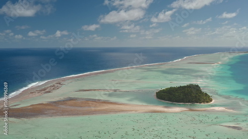 Aerial view of Tikehau island atoll in French Polynesia. Vibrant pink sand and turquoise lagoon, coral reef barrier, and blue ocean under cloudy sky. Remote wild nature paradise, exotic summer travel photo