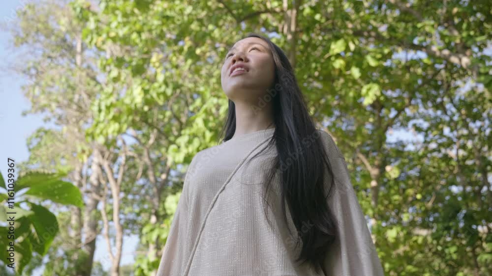 A woman with long hair is standing in a forest, looking up at the sky. The scene is peaceful and serene, with the woman's gaze directed towards the horizon A woman with long hair is standing in a forest, looking up at the sky. The scene is peaceful and serene, with the woman's gaze directed towards the horizon